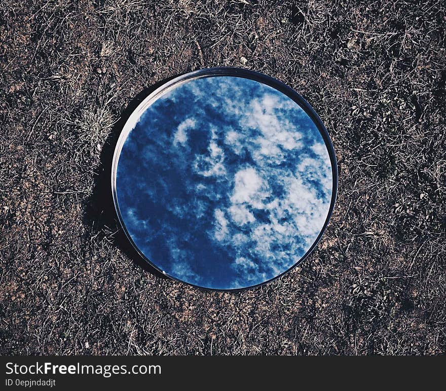 Round mirror lying on grass reflecting blue sky and clouds. Round mirror lying on grass reflecting blue sky and clouds.