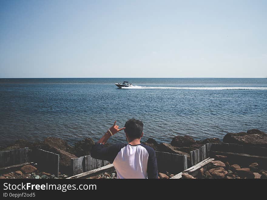 Man Wearing Blue and White T Shirt Next to a Seashore