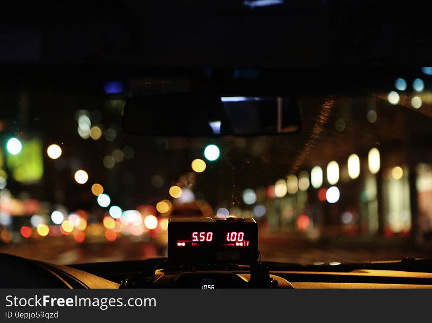 View through windscreen of taxi cab driving through city at night with fare meter in foreground. View through windscreen of taxi cab driving through city at night with fare meter in foreground.