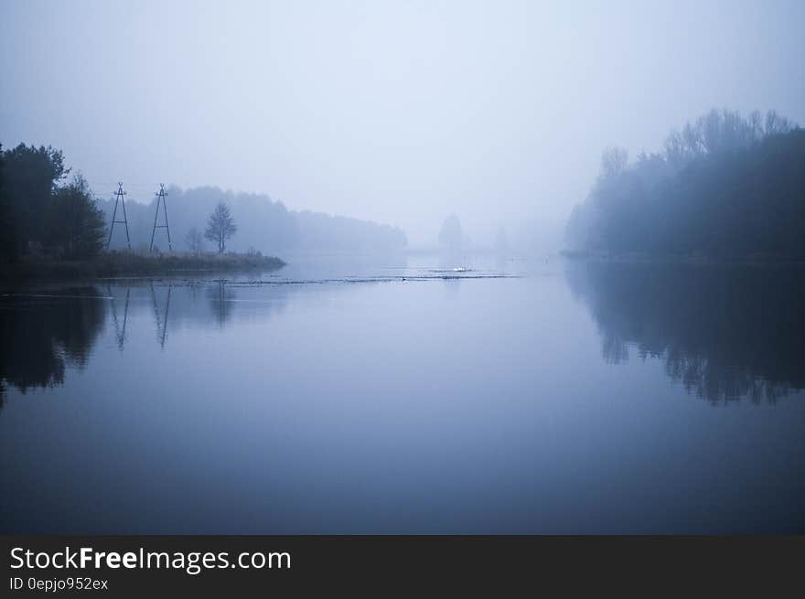 Fog over tree lined river banks in early morning. Fog over tree lined river banks in early morning.