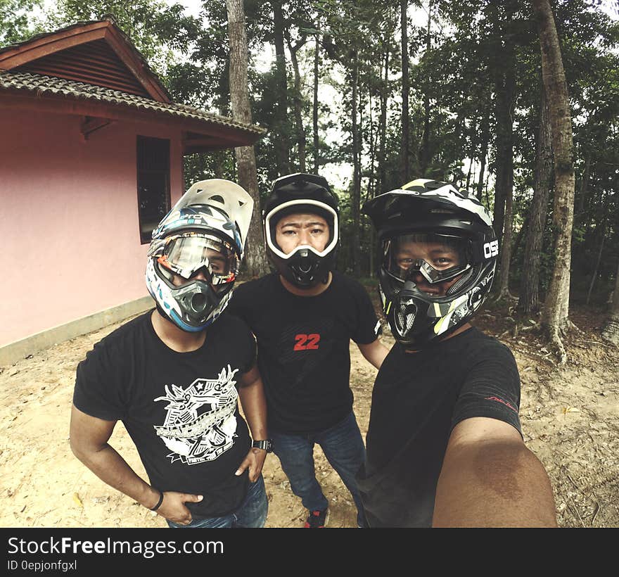 Selfie of group of dirt bikers in helmets outside in woods.