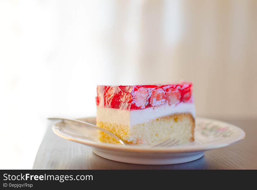 Slice of strawberry dessert cake on small plate with spoon.