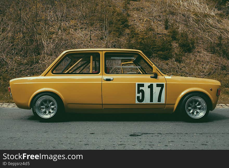 Yellow Sedan Beside Brown Leaf Plant during Daytime