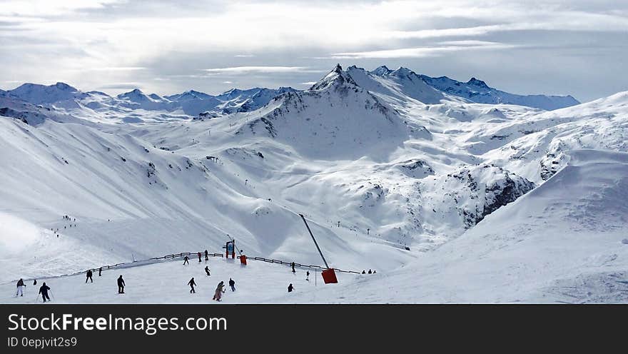 People Lurking Around on Snow Field Near Mountains