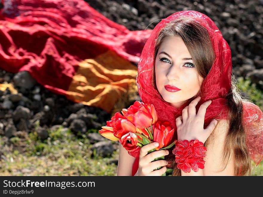 Woman Wearing a Red Scarf Holding Red Flowers