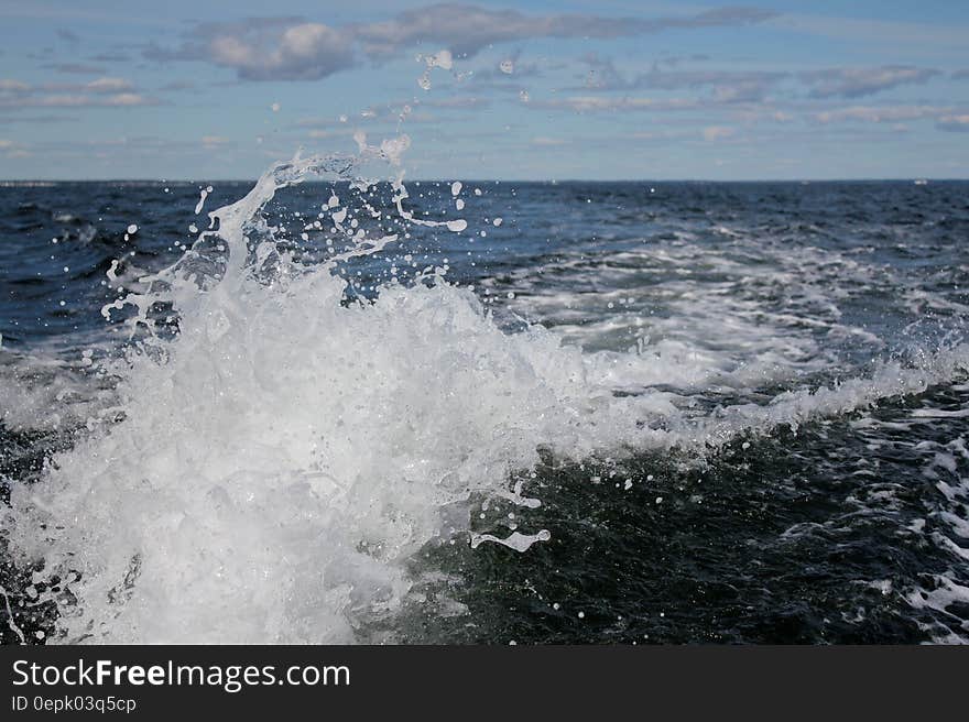 Close up of wave with foam in blue ocean on sunny day. Close up of wave with foam in blue ocean on sunny day.