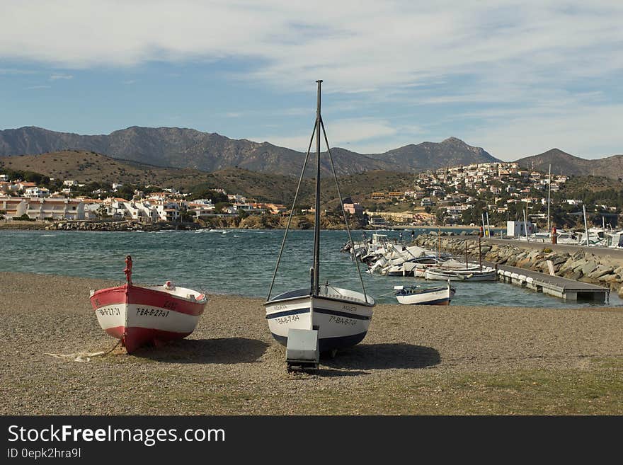 White Red and Black Sail Boat on Gray Sand