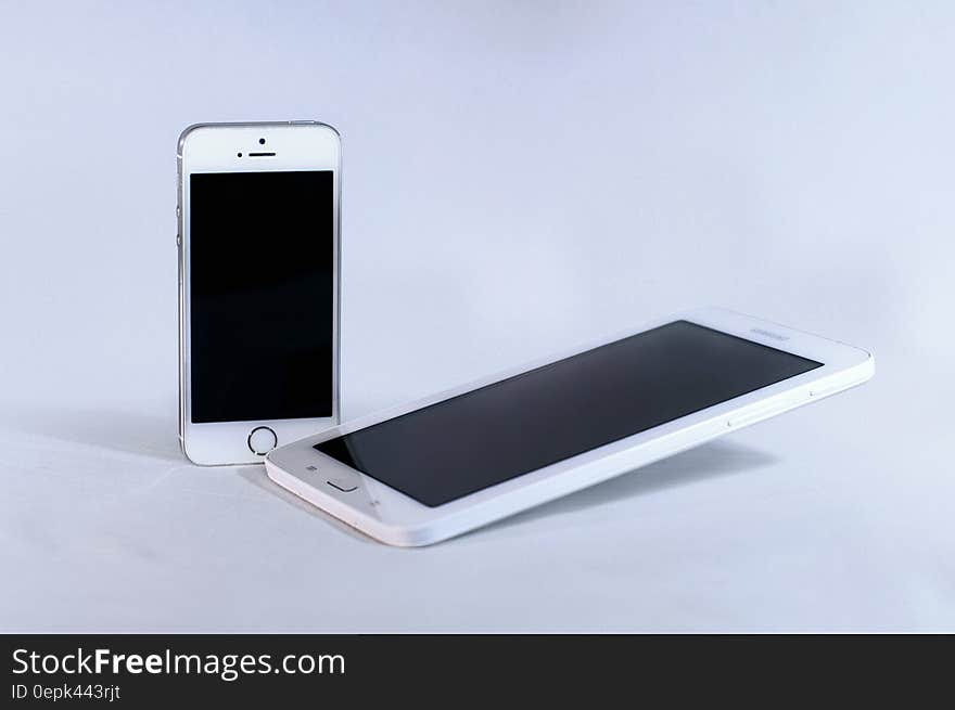 Silver Iphone 5s and White Samsung Android Smartphone