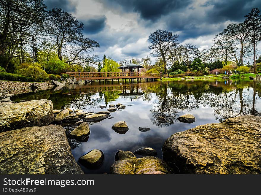 Scenic view of lake in picturesque park with wooden bridge in background. Scenic view of lake in picturesque park with wooden bridge in background.