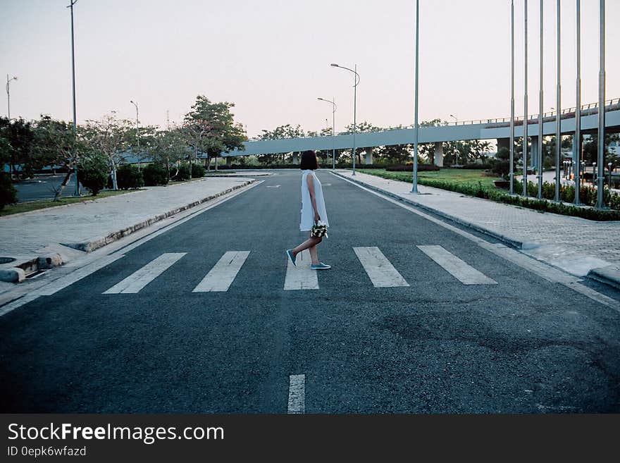 Woman Standing on Gray and White Road Crosswalk