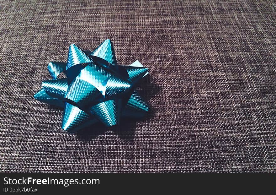 A blue tied up ribbon bow on a piece of fabric. A blue tied up ribbon bow on a piece of fabric.