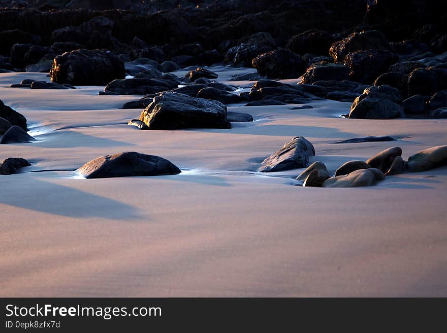 Black Rocks on Sand during Daytime