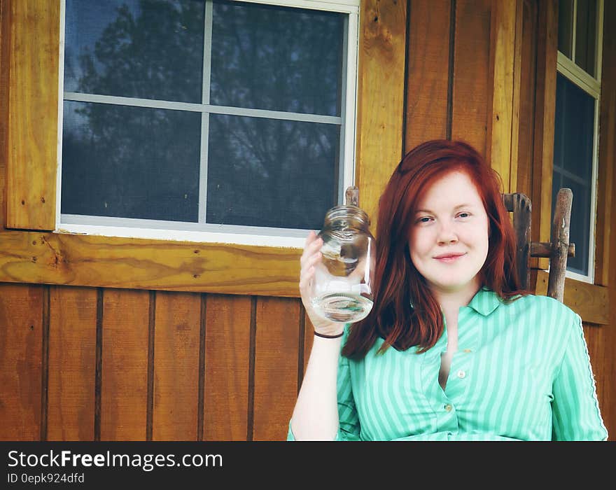 Woman in Green Button Up Collared Shirt Holding Clear Glass