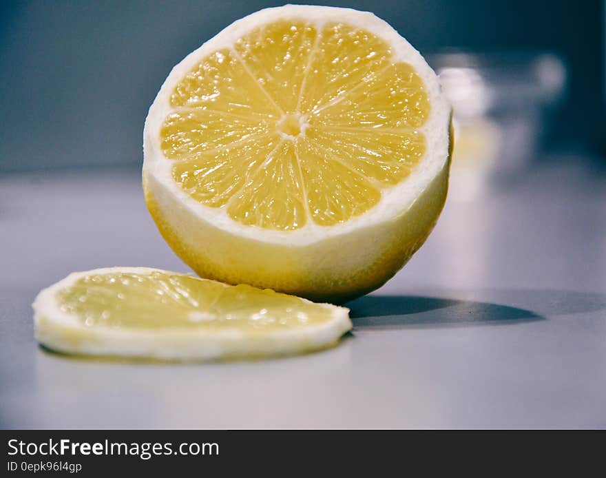 Slice of fresh lemon next to fruit on counter.