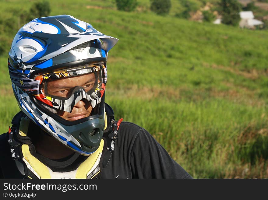 Man Wearing White Blue and Black Motorcycle Helmet during Daytime