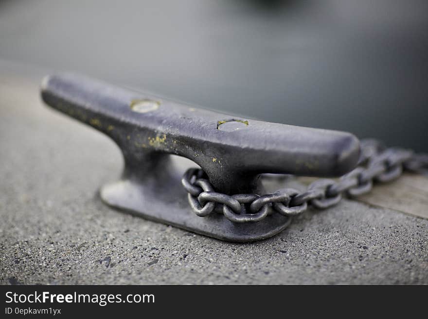 Close up of metal boat tie with chain on waterfront.