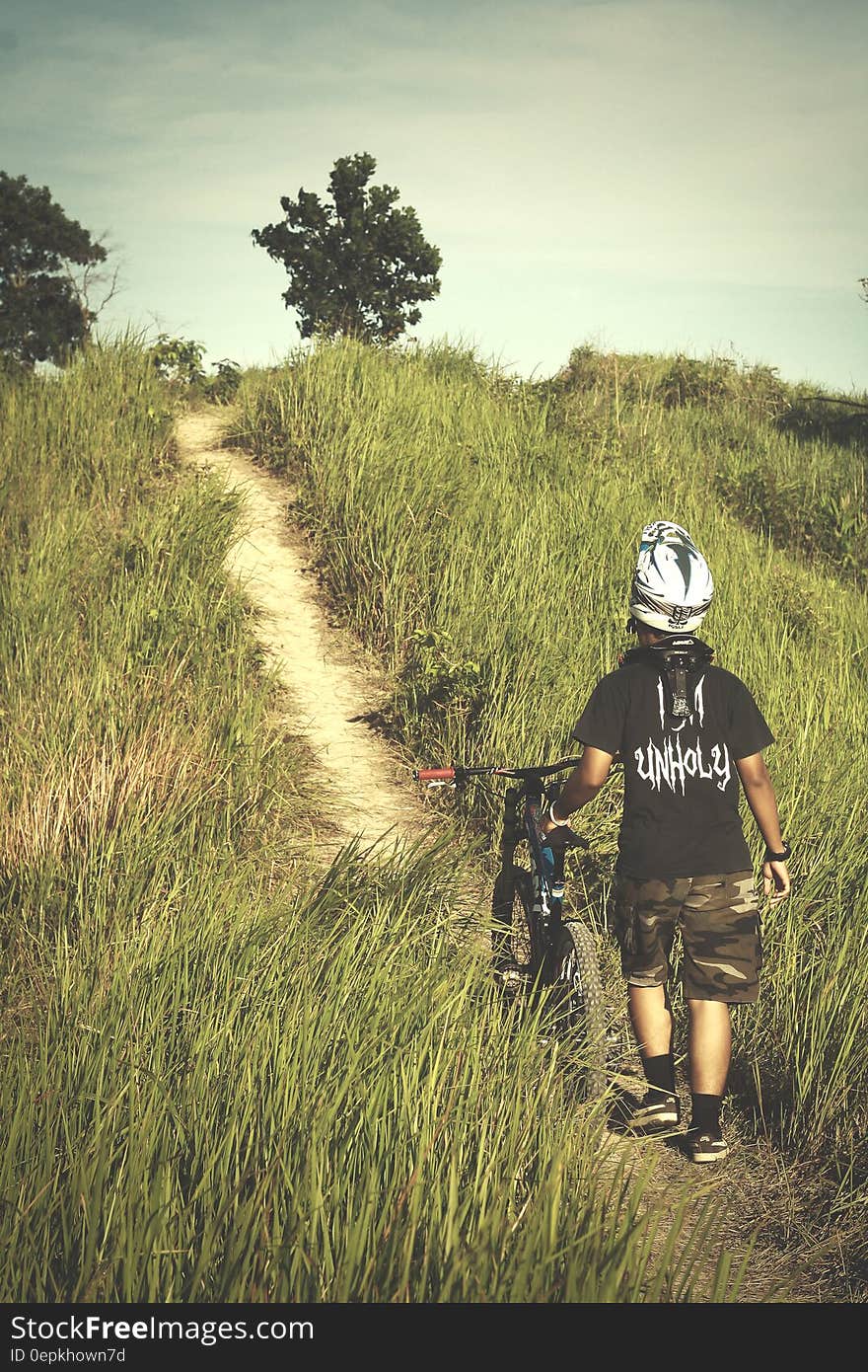 Man in Black Shirt and Brown Shorts Holding Bicycle