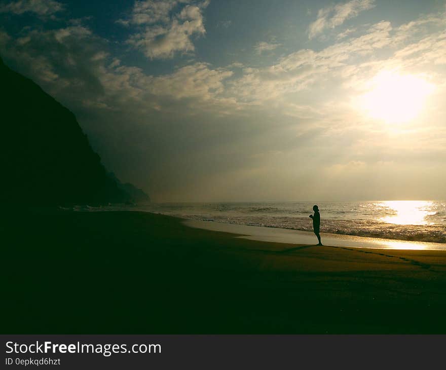 Silhouette of person standing on sandy beach at sunset. Silhouette of person standing on sandy beach at sunset.