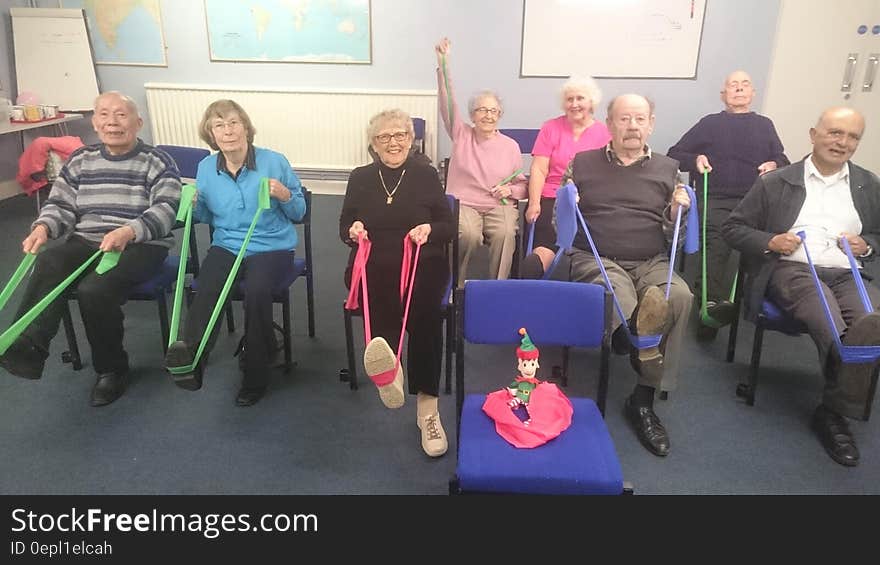 Group of senior citizens exercising with resistance bands in chairs. Group of senior citizens exercising with resistance bands in chairs.