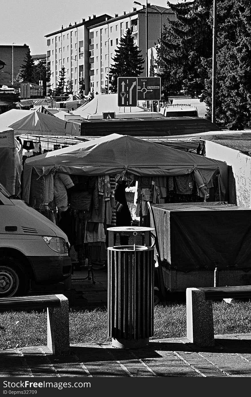 Tents of street fair in urban park in black and white.