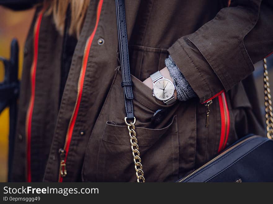 Woman Brown Coat Wearing Silver Analog Watch While Hand in Her Pocket