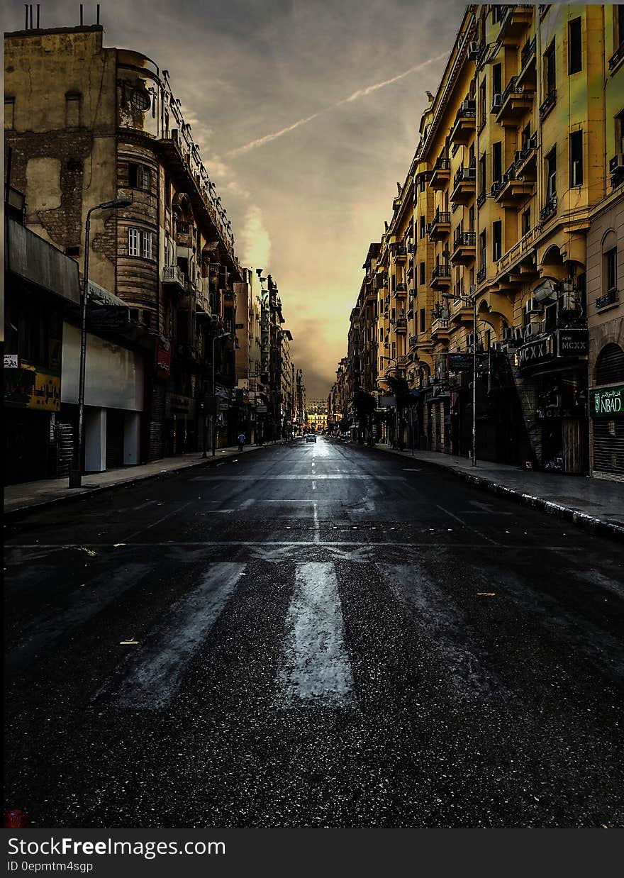 Black Asphalt Road Between Brown City Building Under White Skies during Daytime