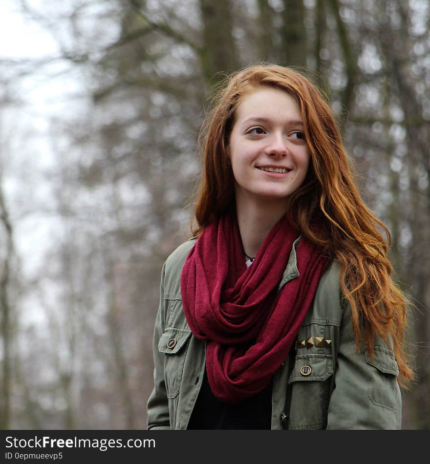 Woman in Green Zip Up Cargo Jacket and Red Scarf Smiling Sideways