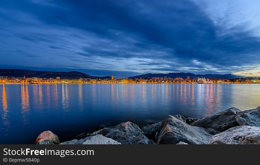 Coastal town reflecting in waterfront at sunset.