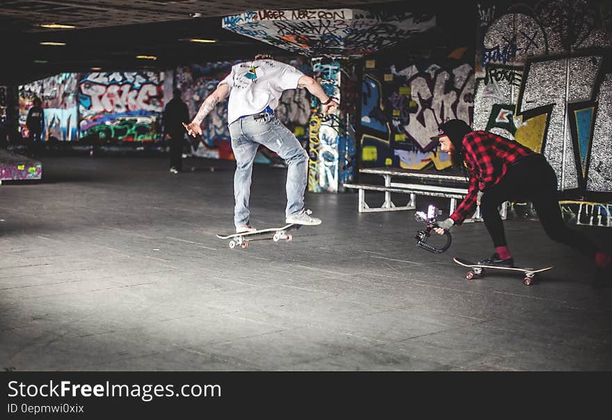 Man in White Shirt on Black Skateboard Doing Tricks