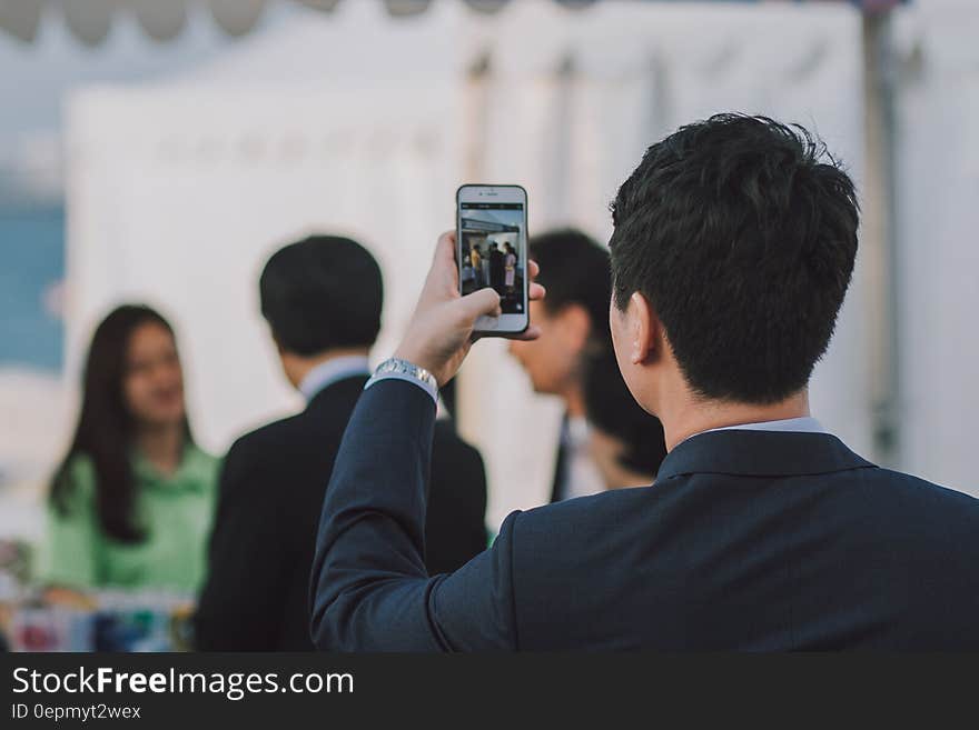 Businessman in suit using smartphone camera in office. Businessman in suit using smartphone camera in office.