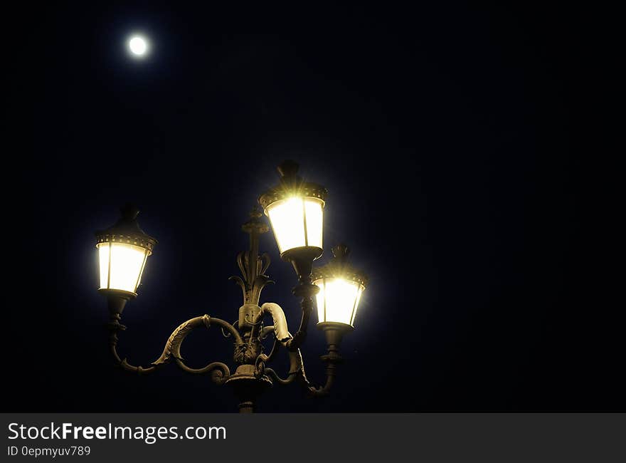 Close up of streetlamp illuminated against night sky with full moon. Close up of streetlamp illuminated against night sky with full moon.