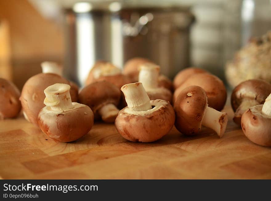 Whole fresh mushrooms on kitchen cutting board.