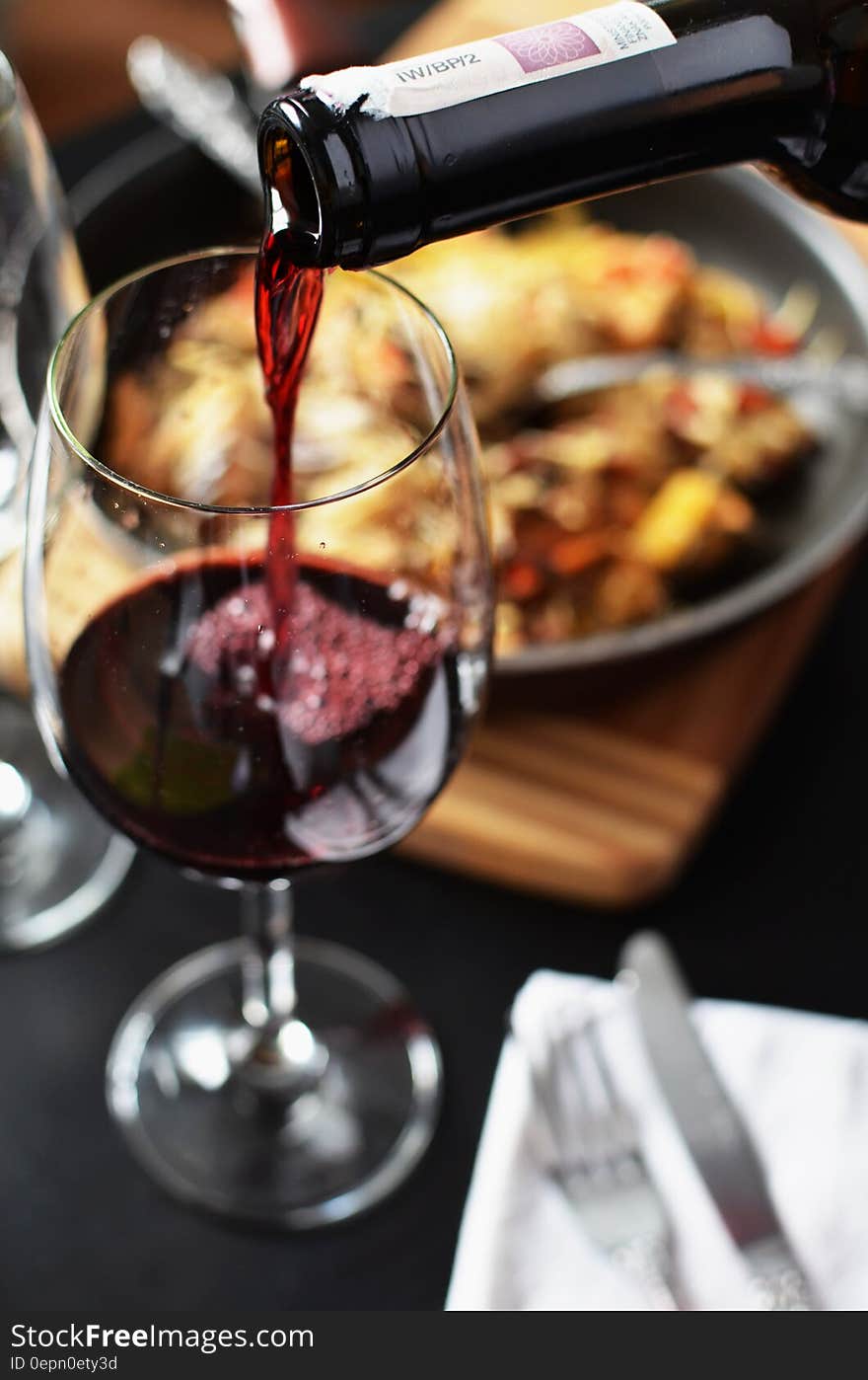 Wine poured from bottle to glass on table with food. Wine poured from bottle to glass on table with food.