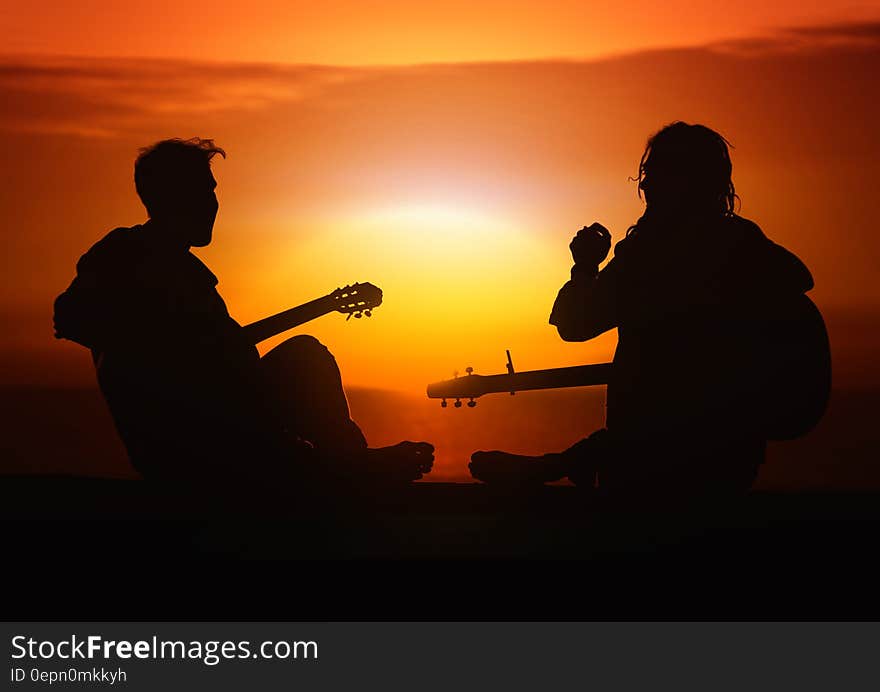 Silhouette of friends playing guitar at sunset. Silhouette of friends playing guitar at sunset.