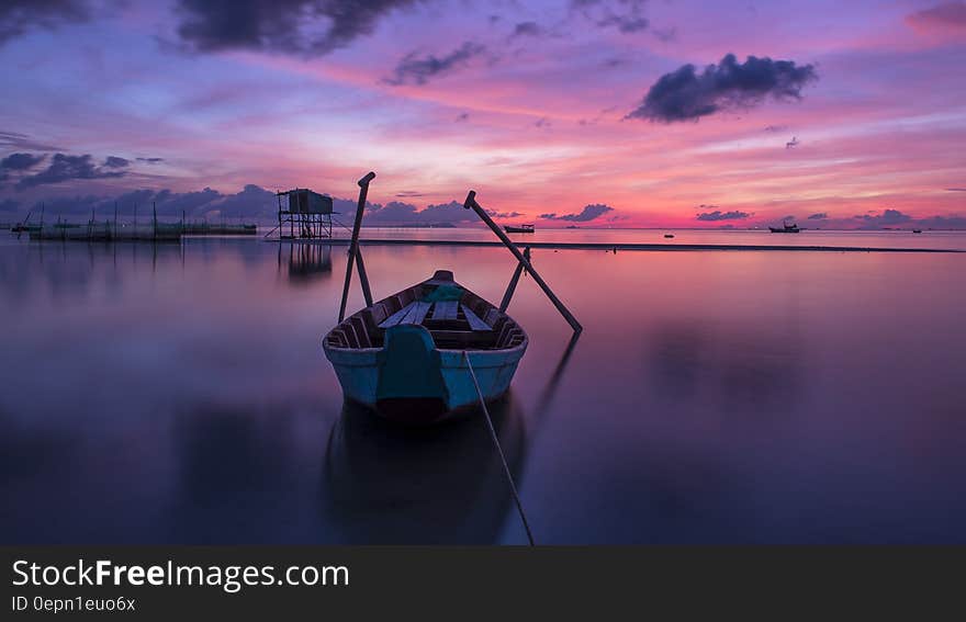 Wooden boat in calm waters at sunset. Wooden boat in calm waters at sunset.