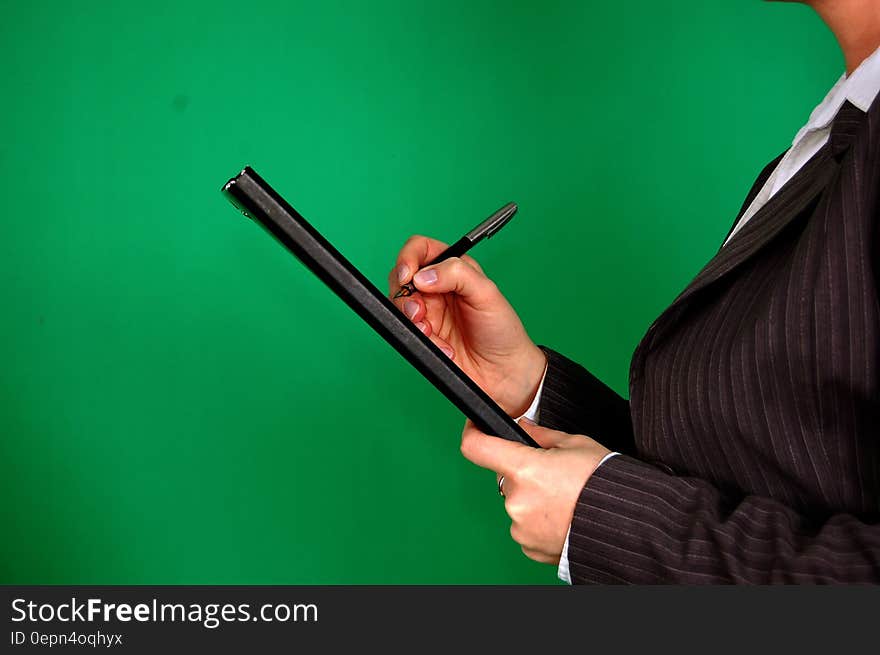 Woman in Gray Pinstripe Blazer Holding Black and Gray Stylus Pen and Black Pad