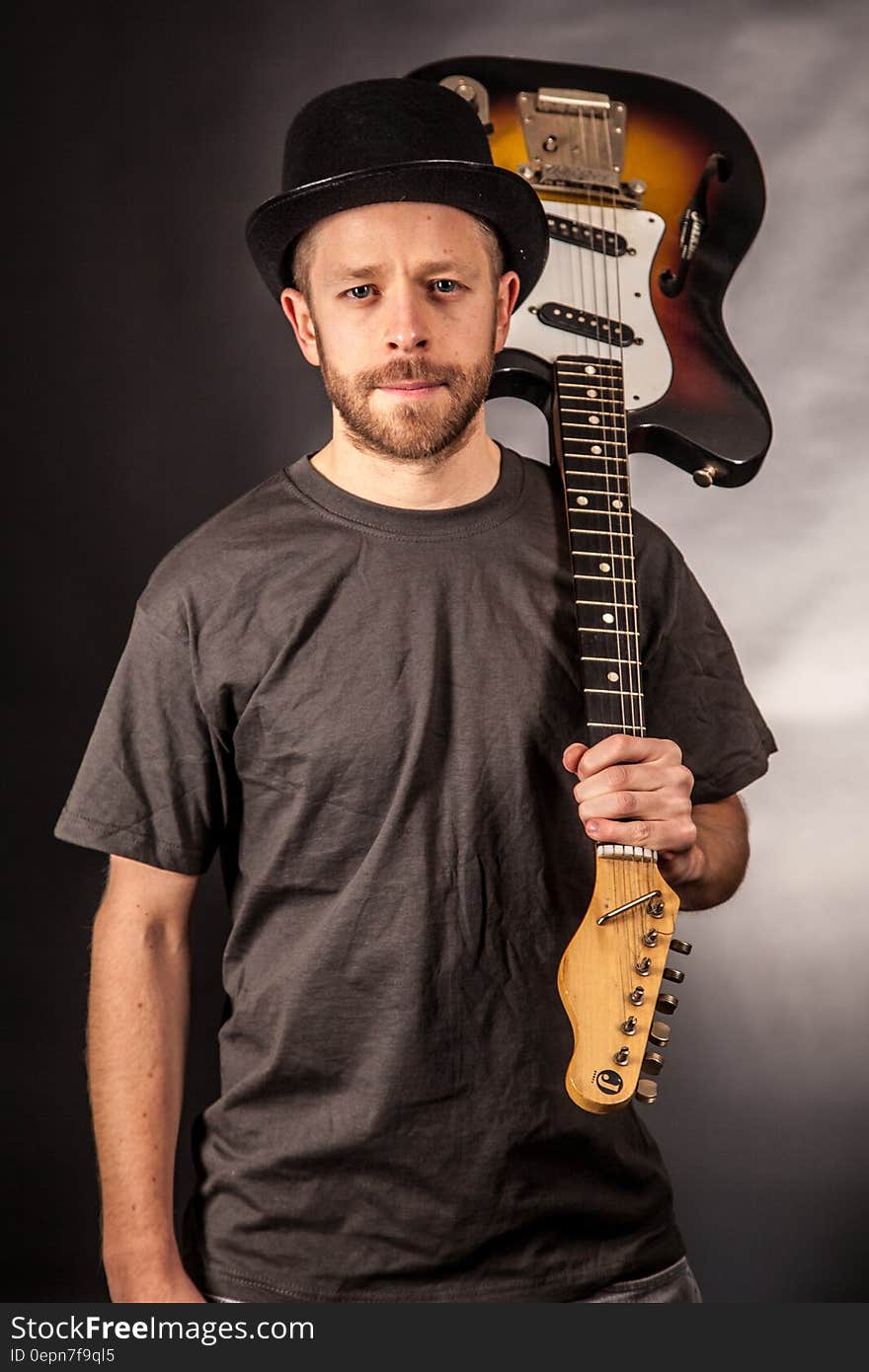 Man in Black T Shirt Holding Electric Guitar Upside Down