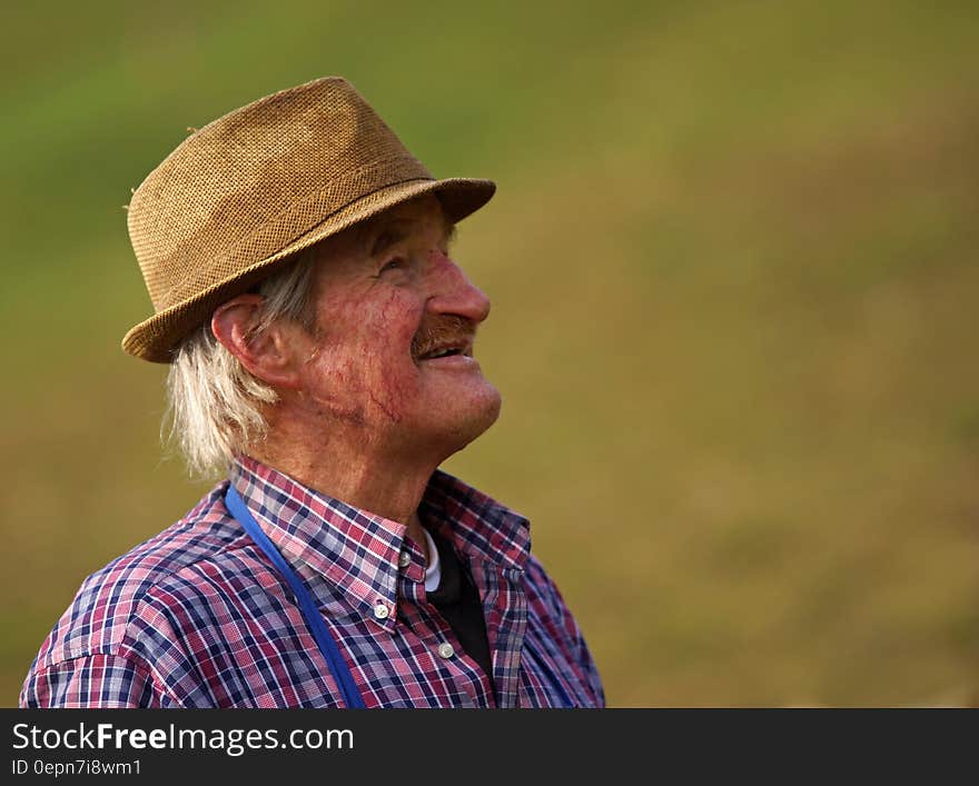 A farmer with a trilby hat and plaid shirt.