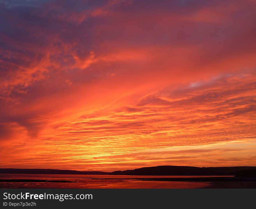 A burning red sky with clouds at sunset.