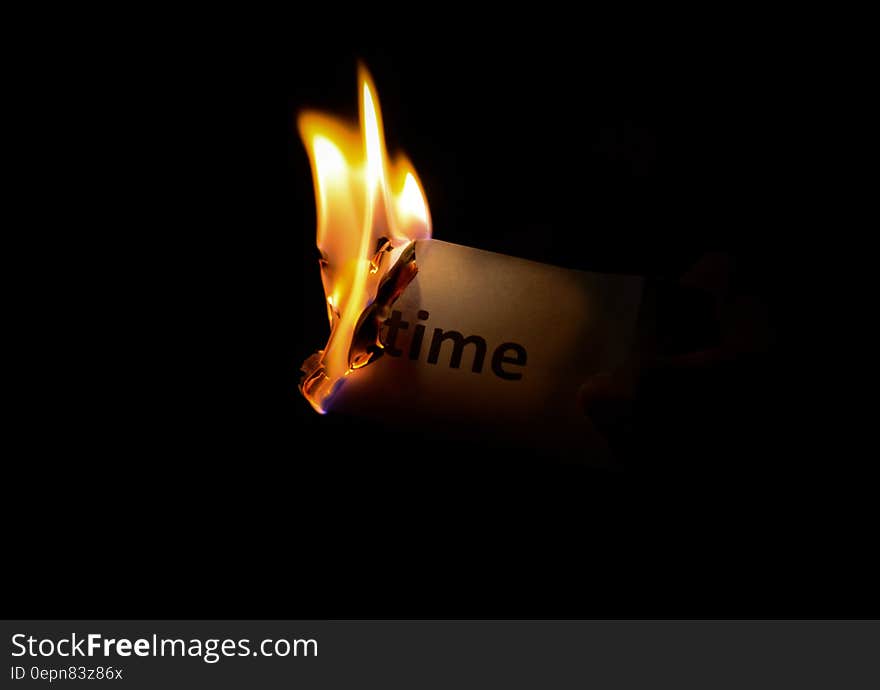 A piece of paper with the word 'time' burning up in flames. A piece of paper with the word 'time' burning up in flames.