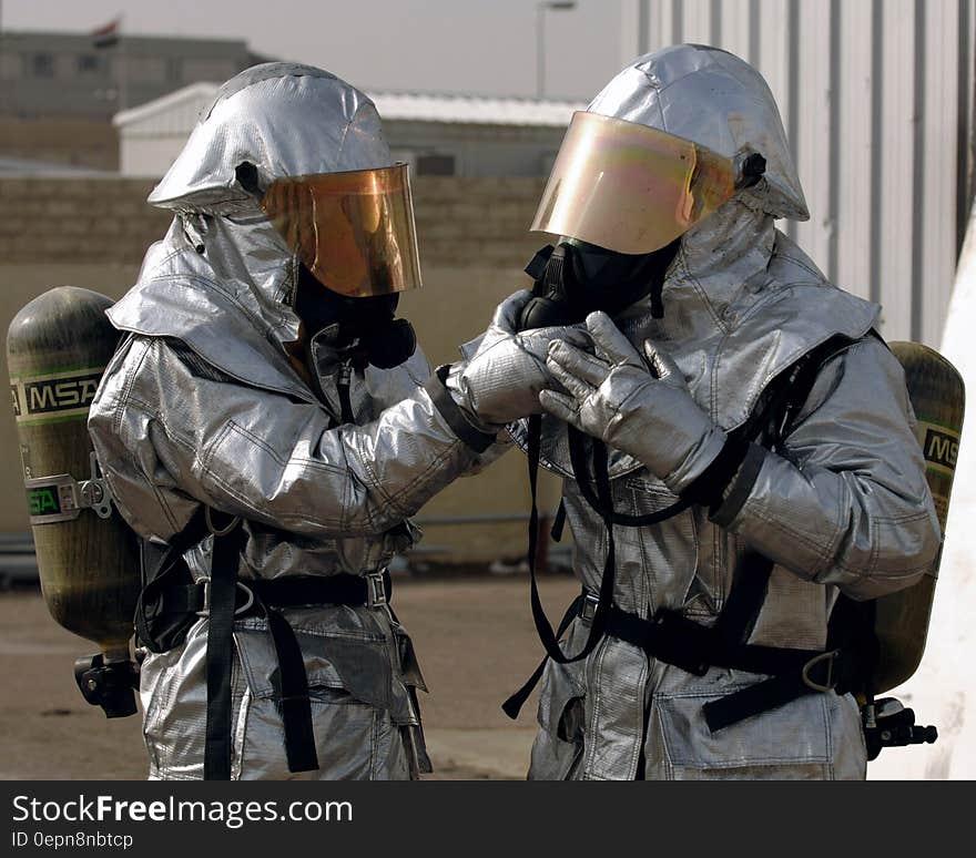 Two firemen in protective suits with gas masks, oxygen bottles and helmets. Two firemen in protective suits with gas masks, oxygen bottles and helmets.