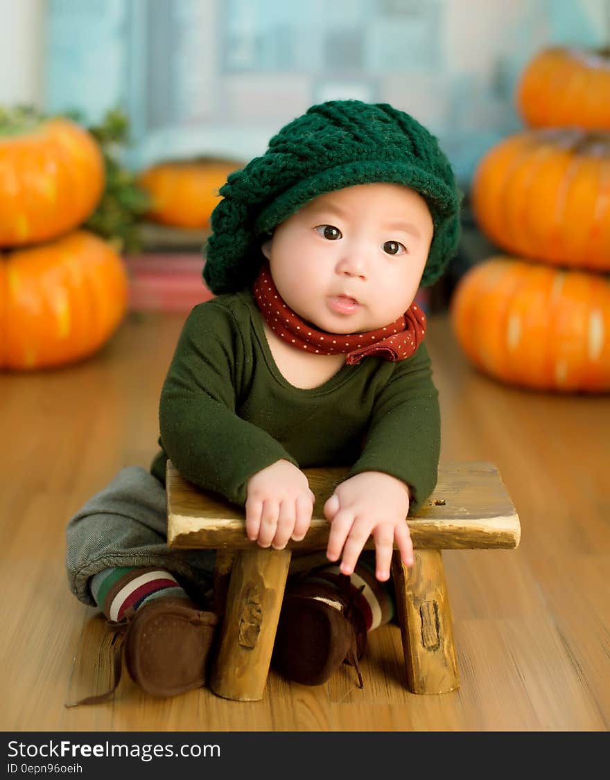 An Asian child leaning on a small stool with pumpkins on the background. An Asian child leaning on a small stool with pumpkins on the background.