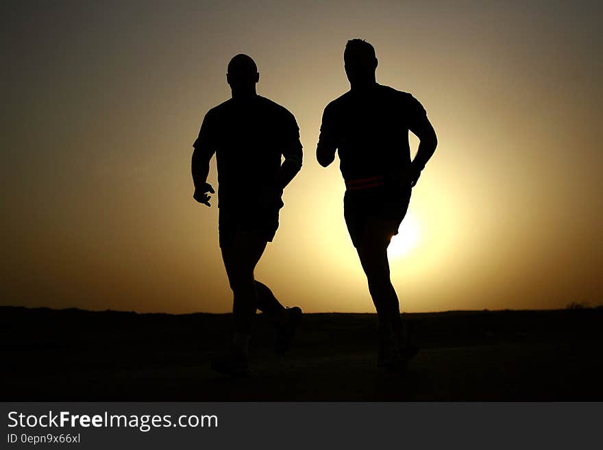 The silhouettes of two runners against the sky. The silhouettes of two runners against the sky.