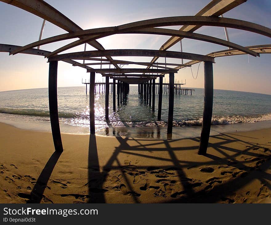 Hull of wooden pier on sandy beach.