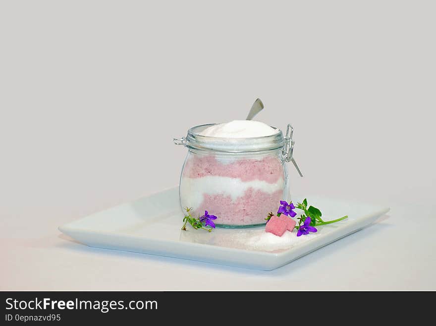 Dessert parfait with whipped cream in glass jar on white plate.