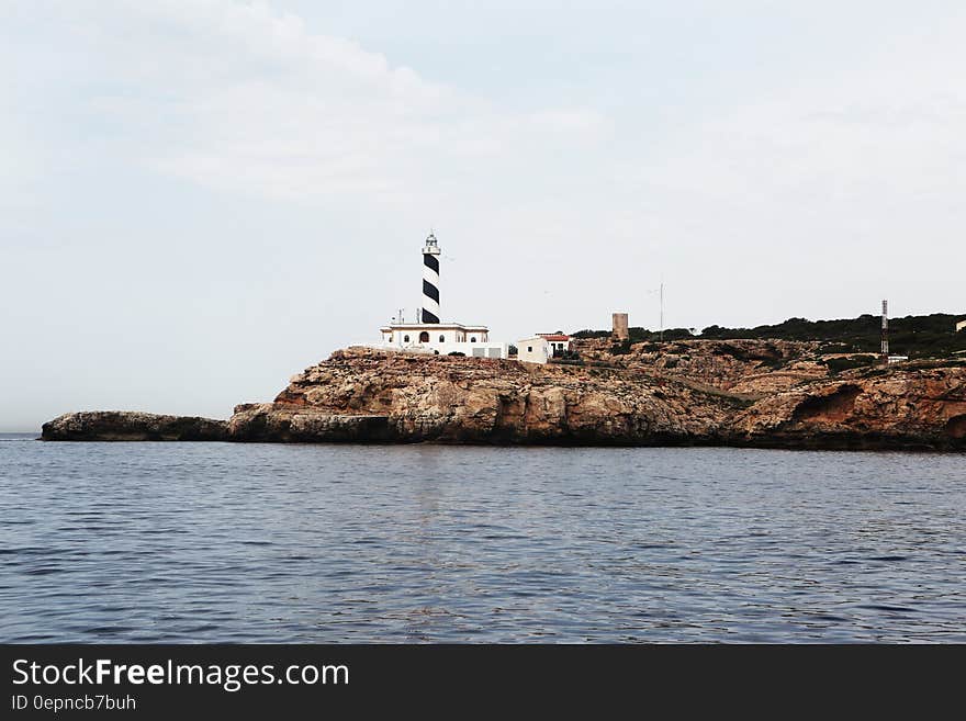 A lighthouse on a rocky cape and still sea surface around. A lighthouse on a rocky cape and still sea surface around.