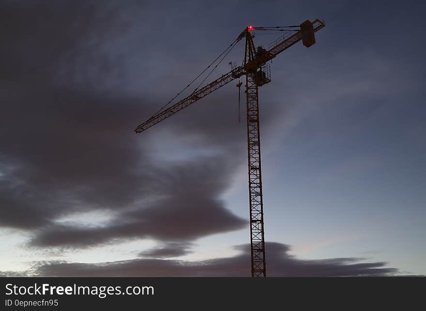 Large modern computerized crane on a construction site with a background of dark thundery threatening clouds. Large modern computerized crane on a construction site with a background of dark thundery threatening clouds.