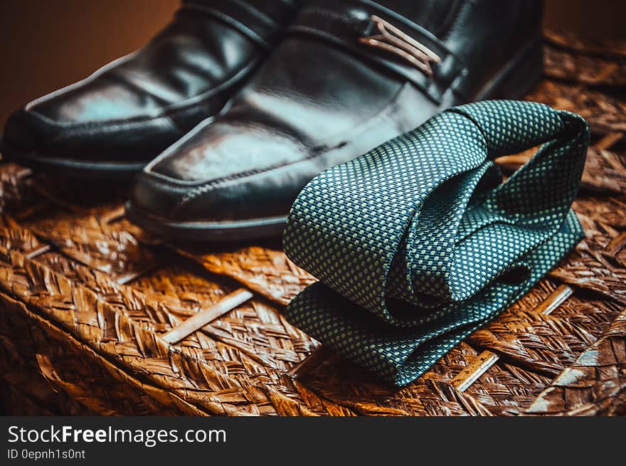 Man&#x27;s Black Leather Shoes Near to Green and White Spotted Tie