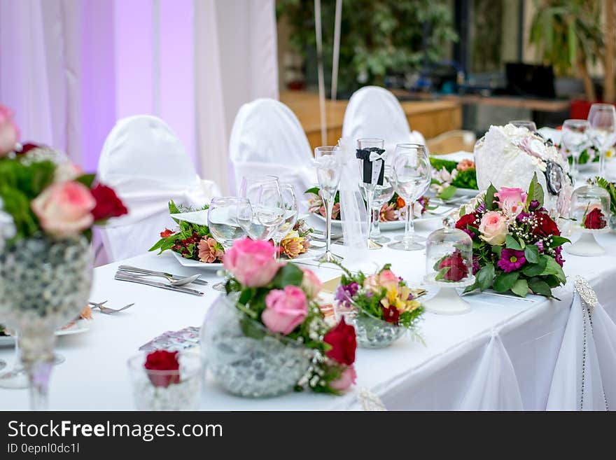 Formal banquet table with white linens and flowers decorated for wedding. Formal banquet table with white linens and flowers decorated for wedding.