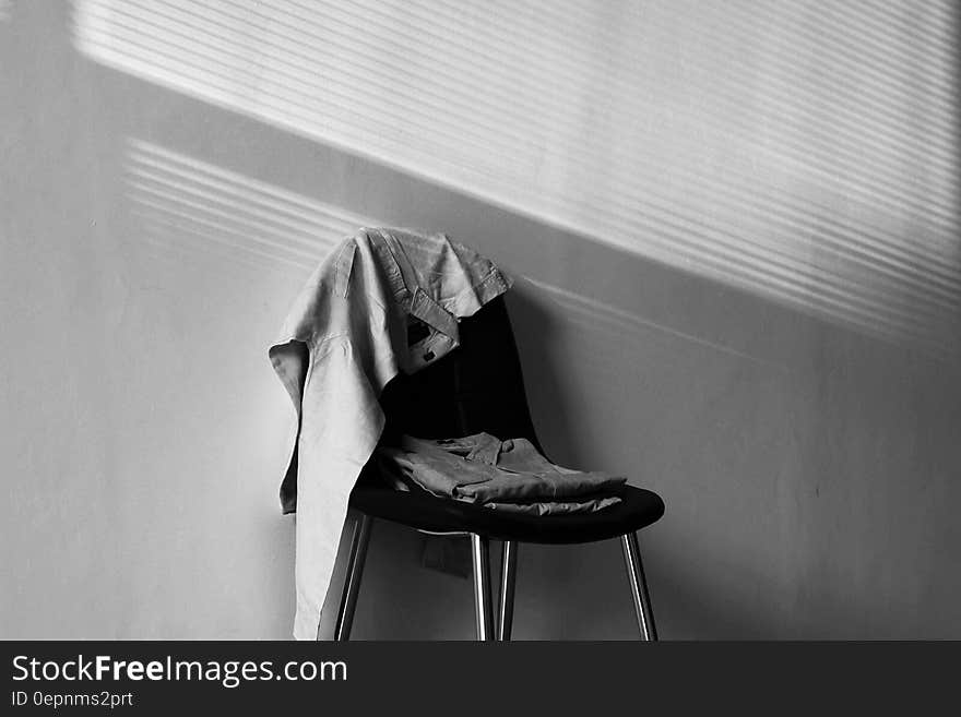 Clothes on chair in room in black and white.